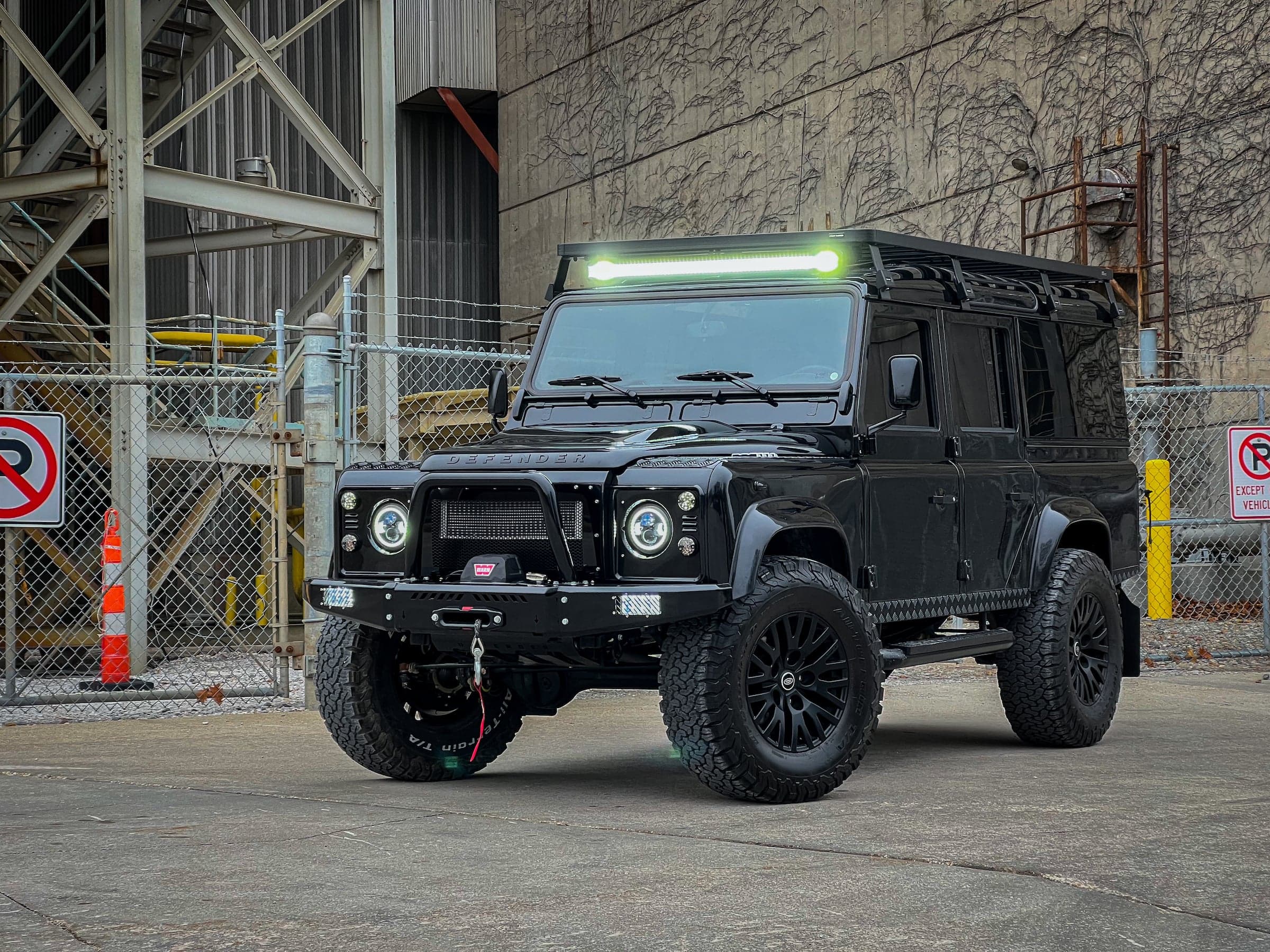 Custom black Land Rover Defender with off-road capabilities and LED light bar