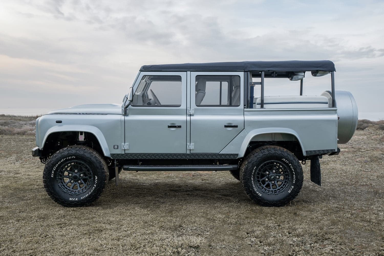 Custom Land Rover Defender in a light silver finish with off-road tires and a soft top