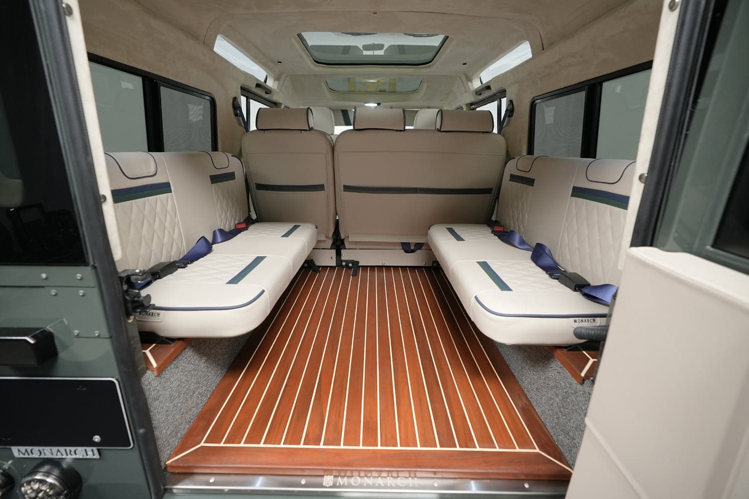 Interior view of a custom Land Rover Defender featuring luxurious seating and wooden flooring