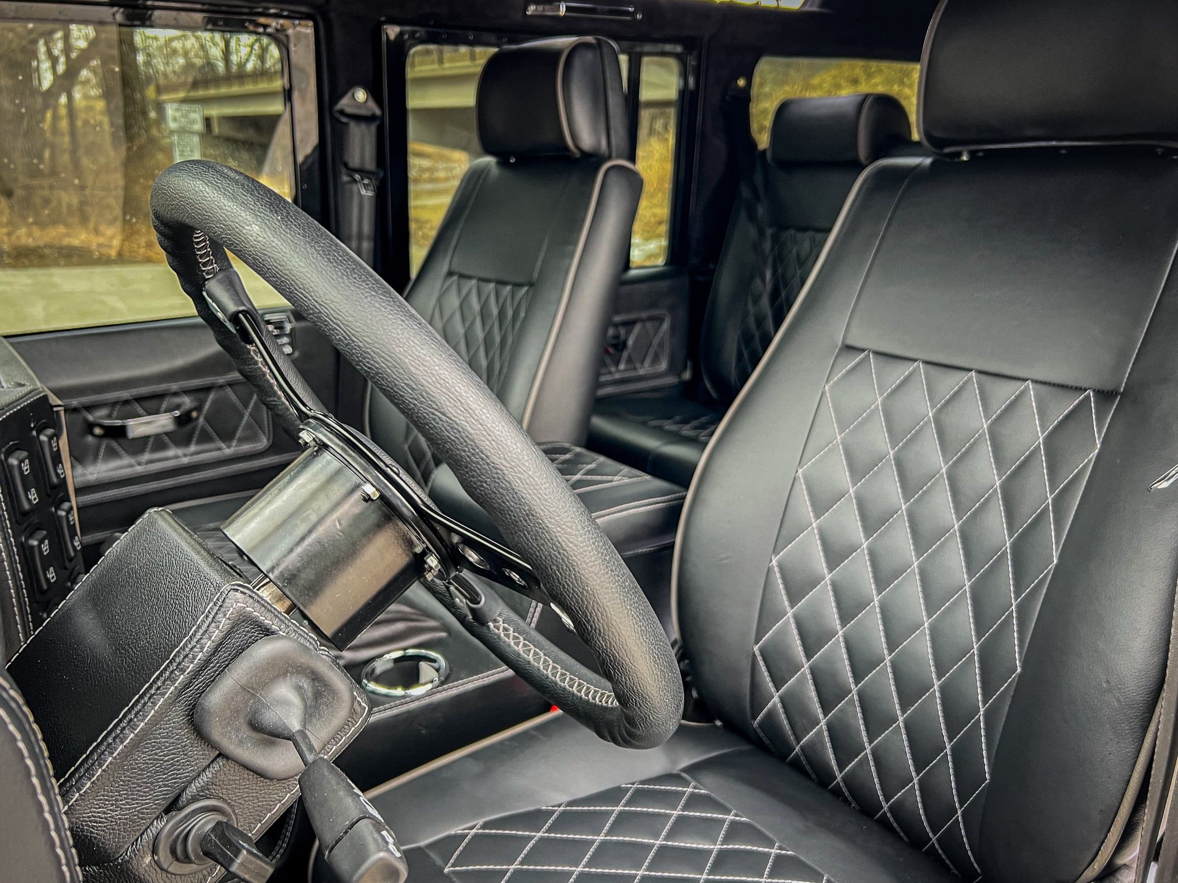 Interior view of a custom Land Rover Defender showcasing premium black leather seats with diamond stitching