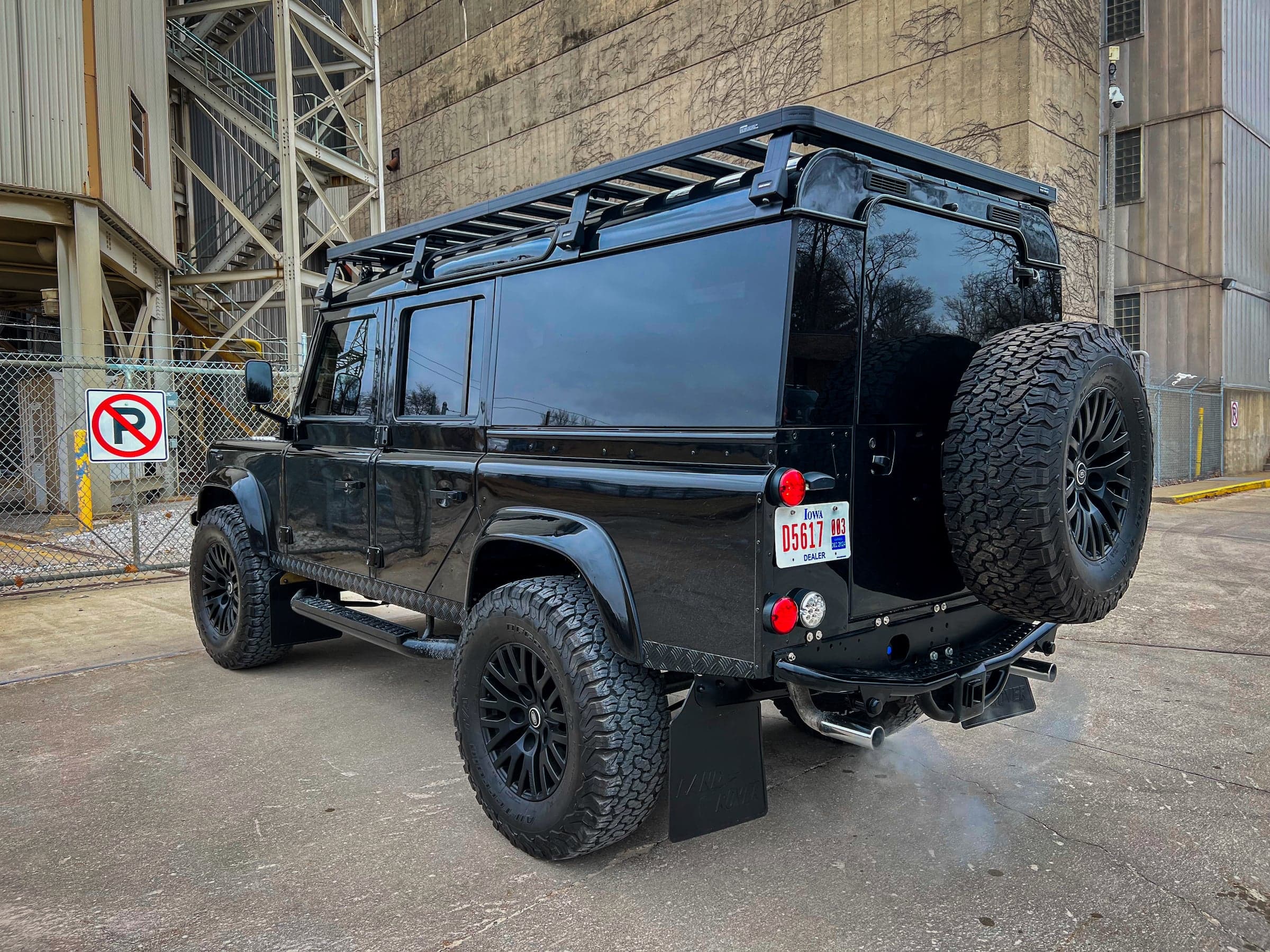 Black modified Land Rover Defender with off-road tires and roof rack