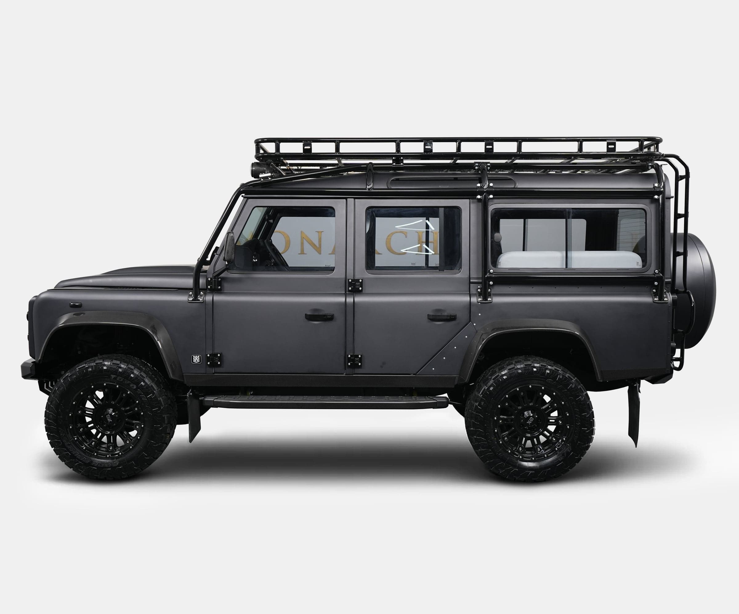Side view of a bespoke Land Rover Defender with a matte black finish and rugged off-road tires
