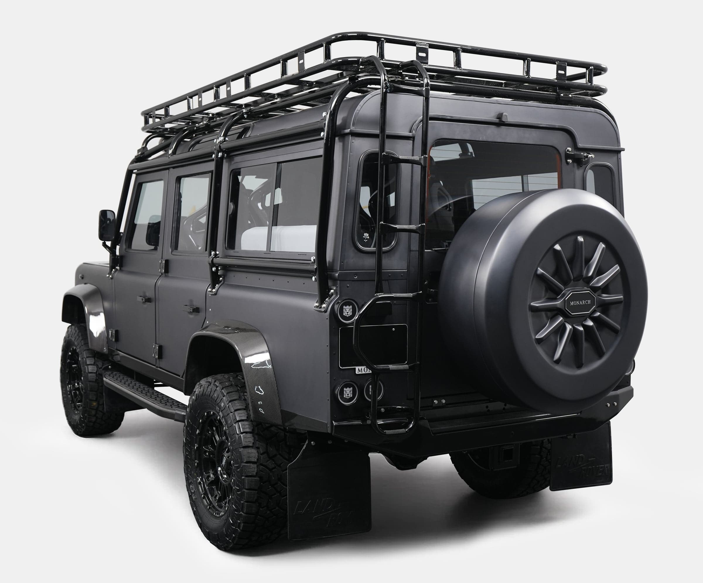 Rear view of a custom Land Rover Defender with a black matte finish and roof rack