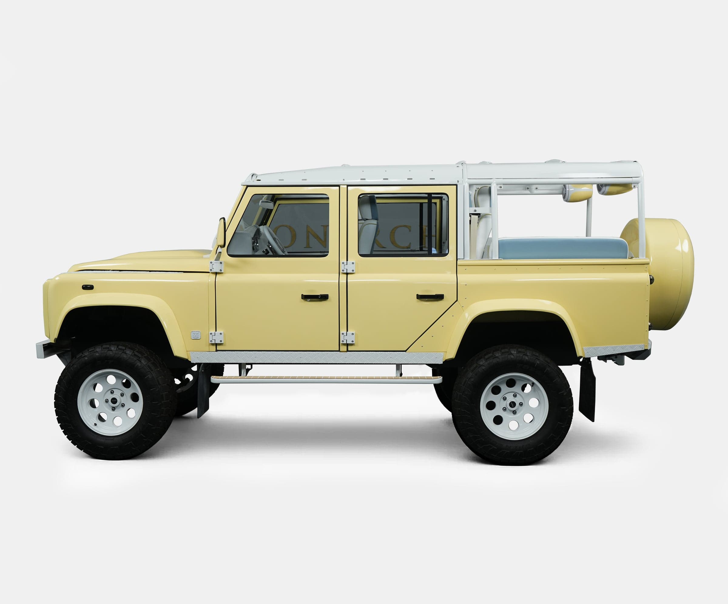 Side view of a bespoke Land Rover Defender in a soft yellow color with custom features