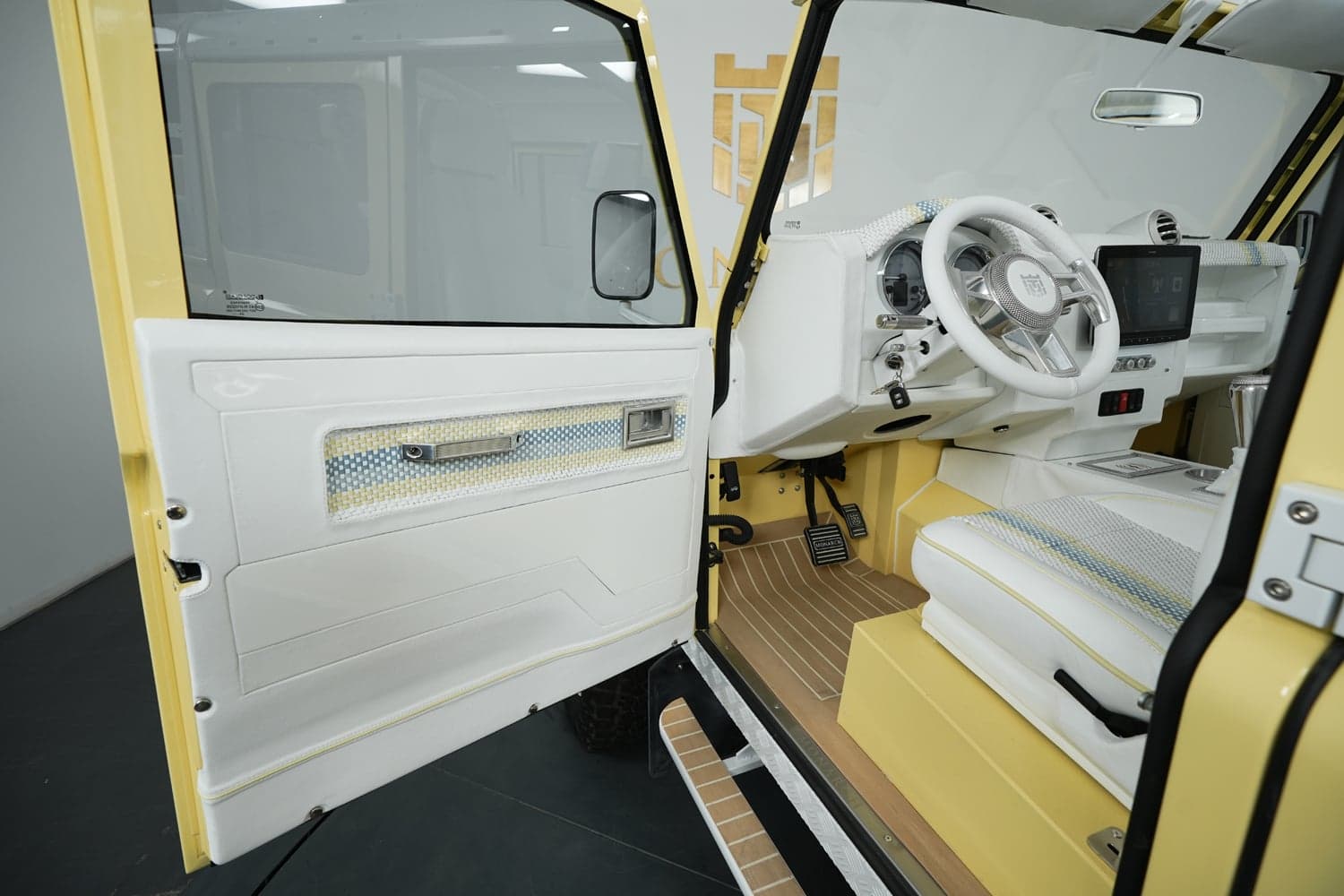 Interior view of a luxury custom Land Rover Defender featuring white leather upholstery and yellow accents