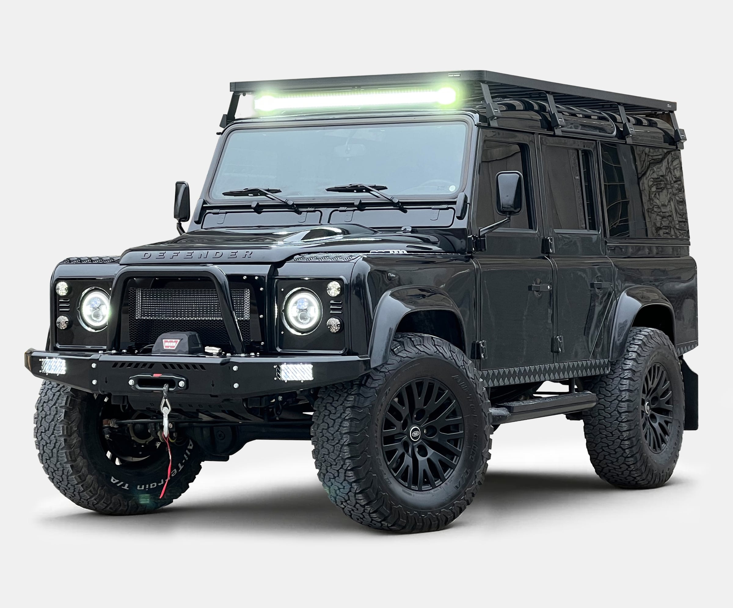 Custom black Land Rover Defender with off-road features and LED light bar