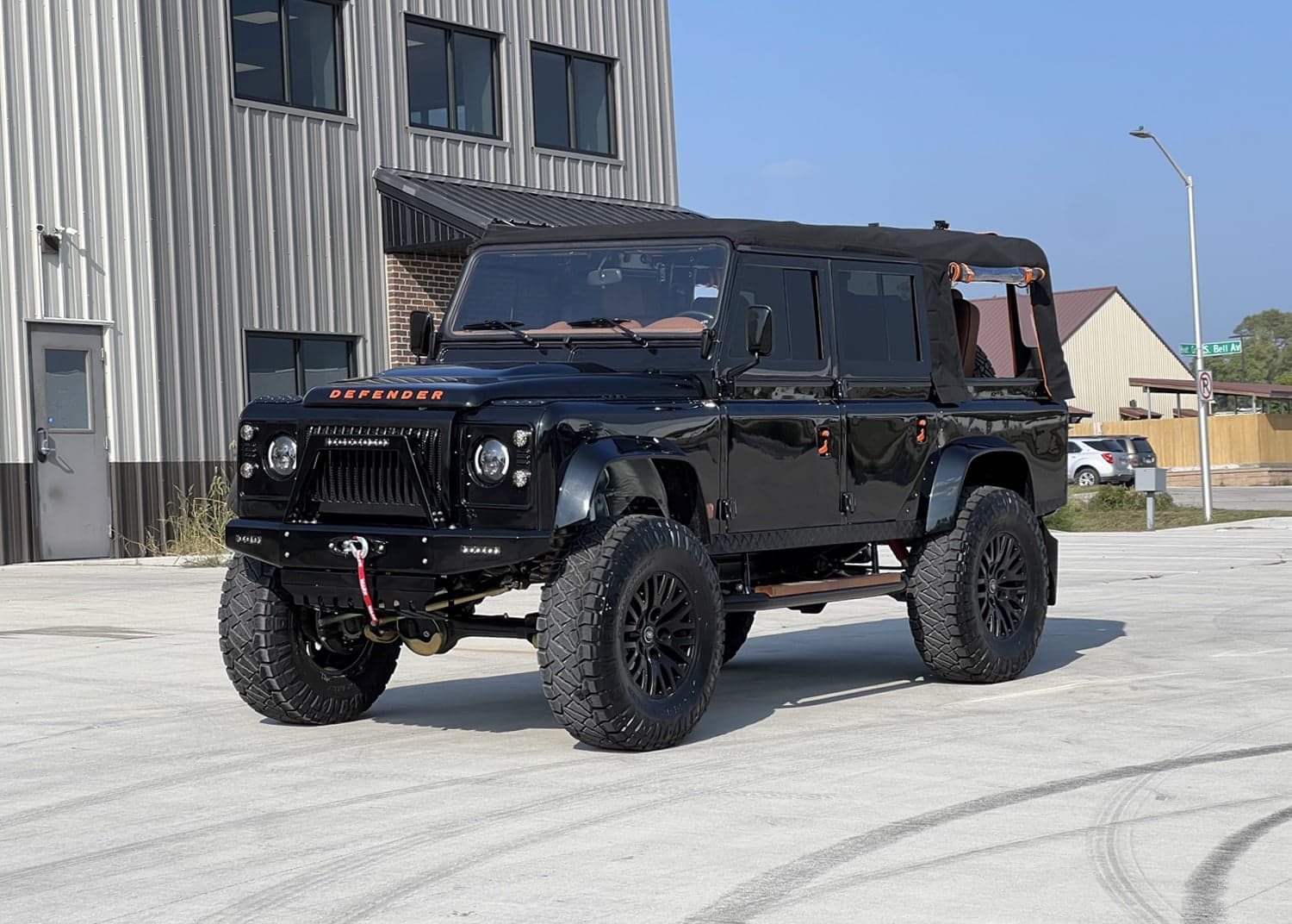 Front View: Bespoke Land Rover Defender Custom black Land Rover Defender with a soft top and rugged tires