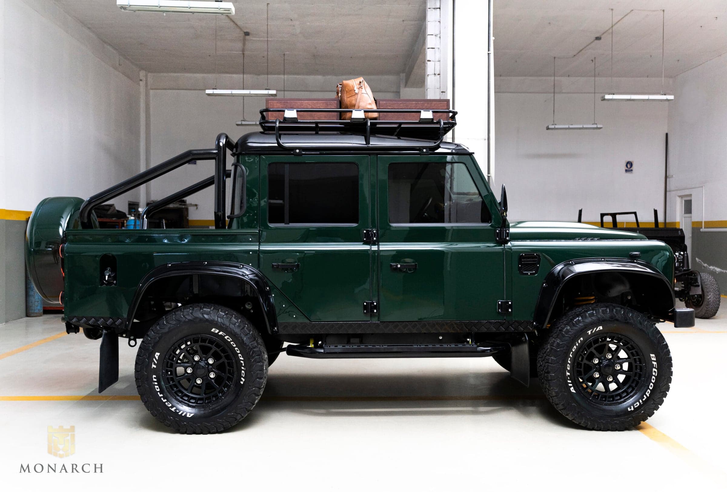 Side View: Bespoke Land Rover Defender Side view of a custom green Land Rover Defender with off-road tires and roof rack