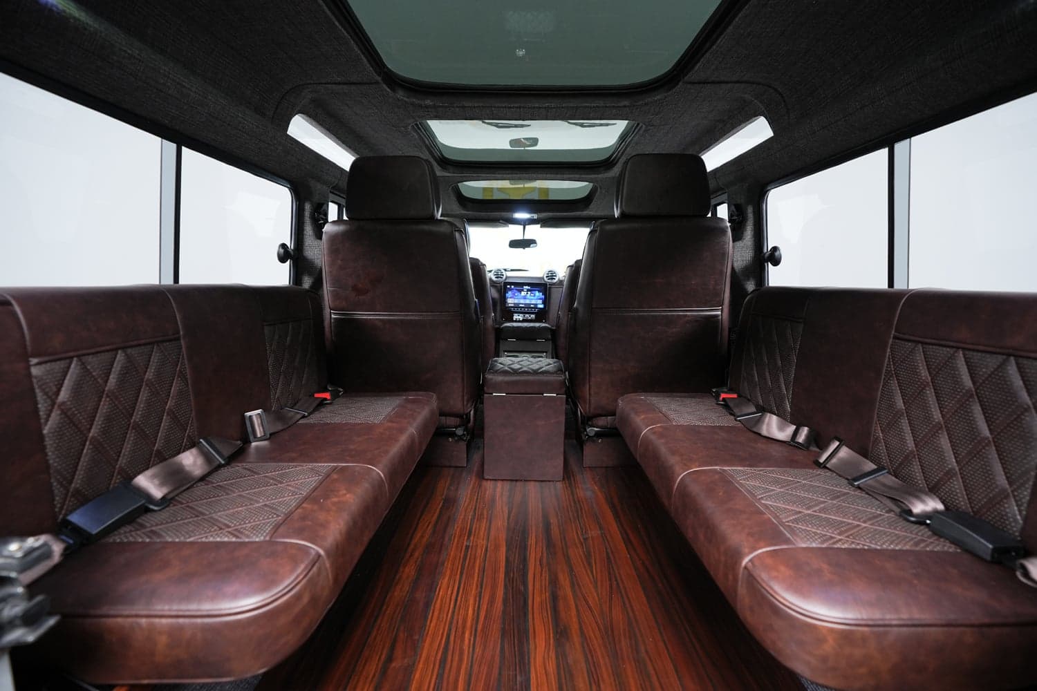 Interior Shot: Luxurious Cabin Design Interior view of a luxury Land Rover Defender featuring rich brown leather seats and polished wooden flooring