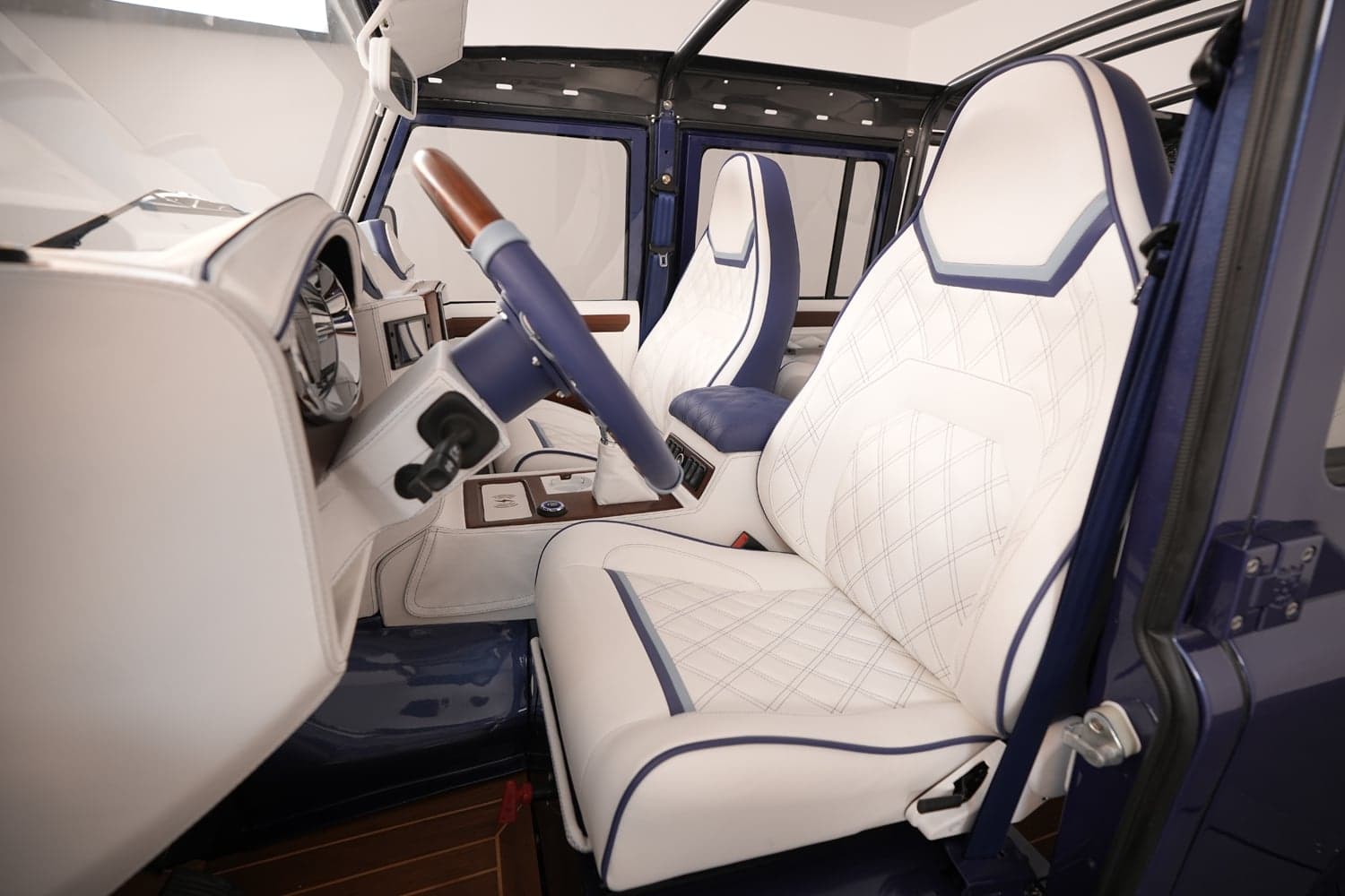 Interior Shot: Luxury Cabin Design Luxury custom Land Rover Defender interior with white quilted leather seats and blue accents