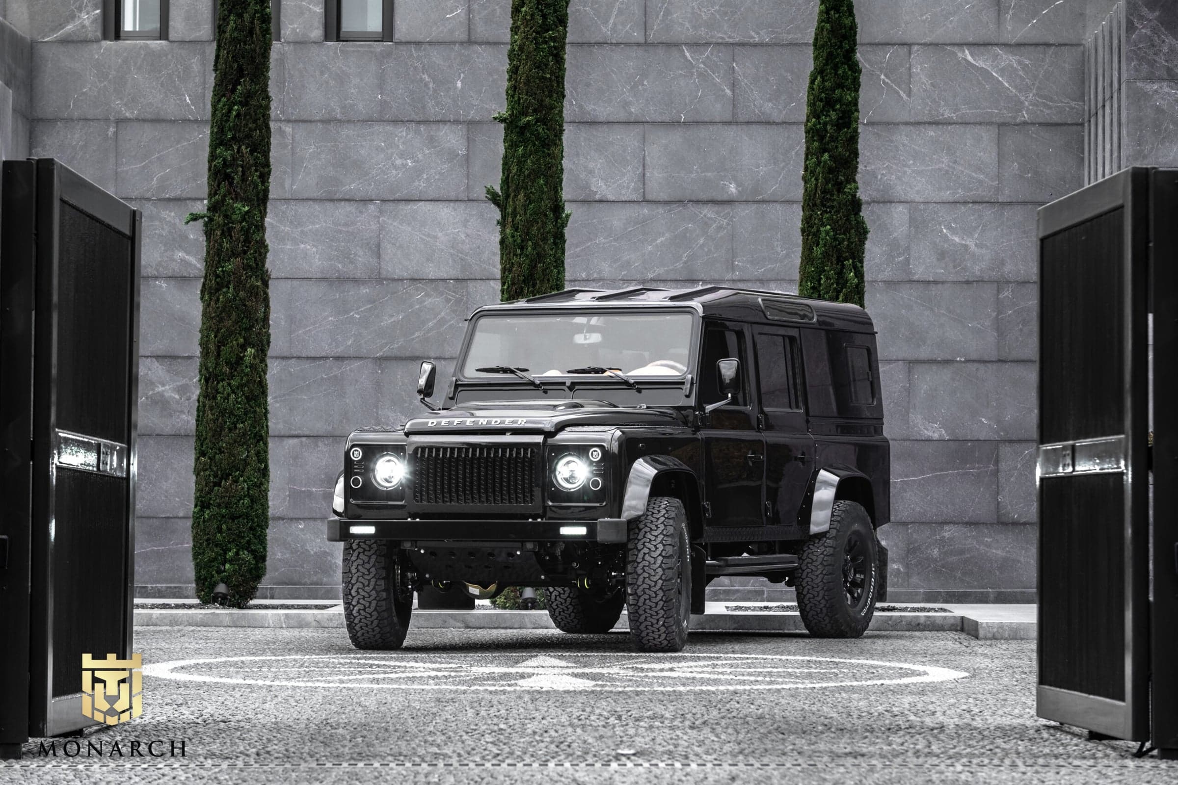 Front View: Bespoke Land Rover Defender Custom black Land Rover Defender parked in a modern setting