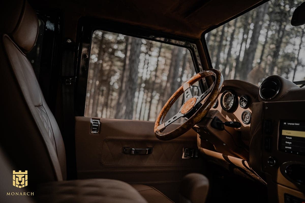 Interior Shot: Luxurious Cabin Design Interior view of a custom Land Rover Defender featuring a premium leather seat and wooden steering wheel