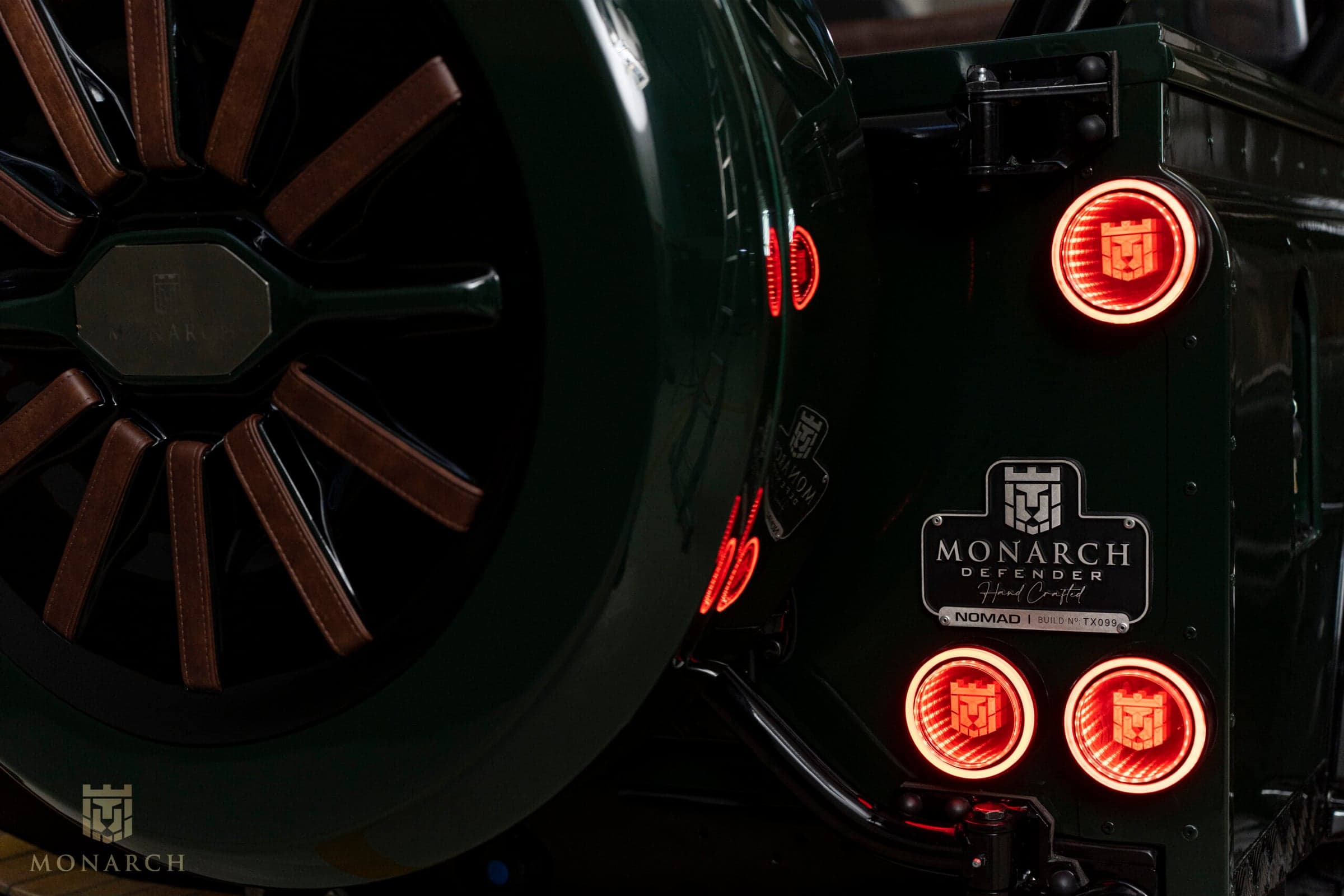 Detail Shot: Custom Wheel and Tail Lights Close-up of a bespoke Land Rover Defender wheel with brown leather accents and illuminated tail lights