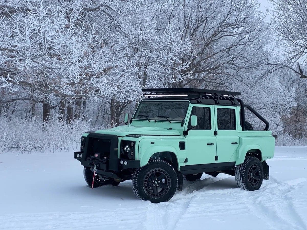 Front View: Bespoke Land Rover Defender Mint green custom Land Rover Defender parked in a snowy landscape