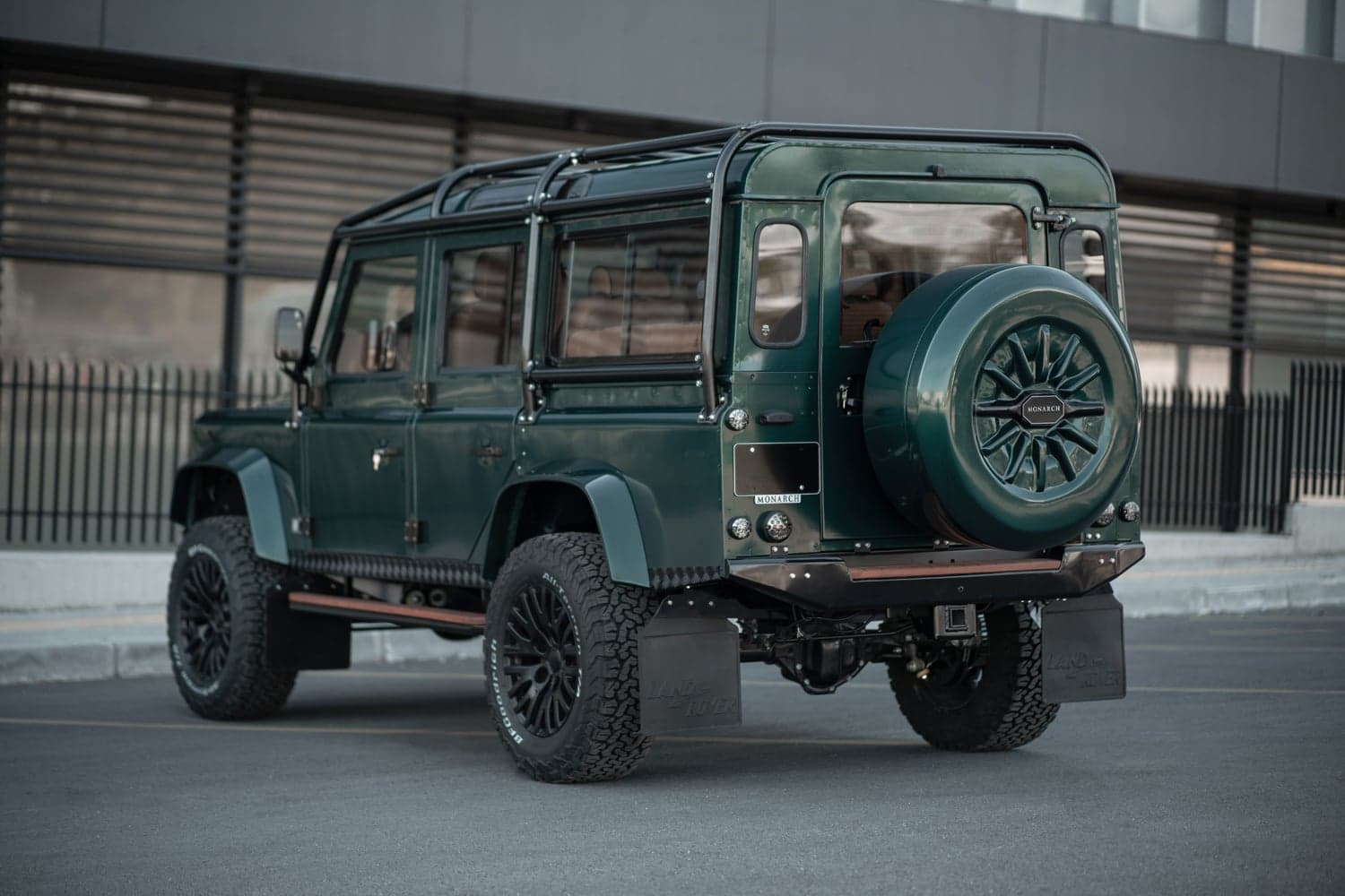 Rear View: Bespoke Land Rover Defender Rear view of a green custom Land Rover Defender with premium off-road tires and a spare tire mounted on the back