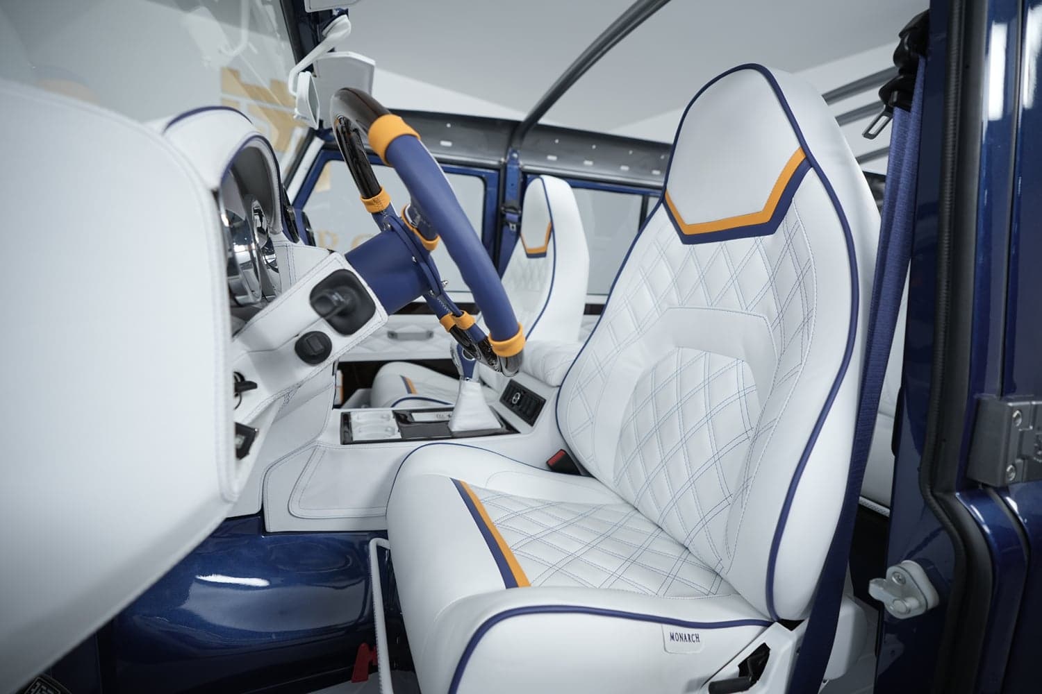 Interior Shot: Luxury Cabin Design Custom Land Rover Defender interior featuring white leather seats with orange and blue accents