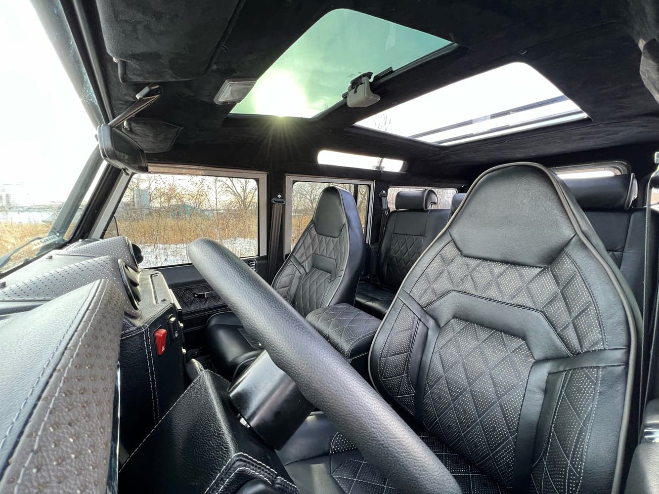 Interior Shot: Luxury Cabin Interior view of a custom Land Rover Defender showcasing black leather seats and modern design elements