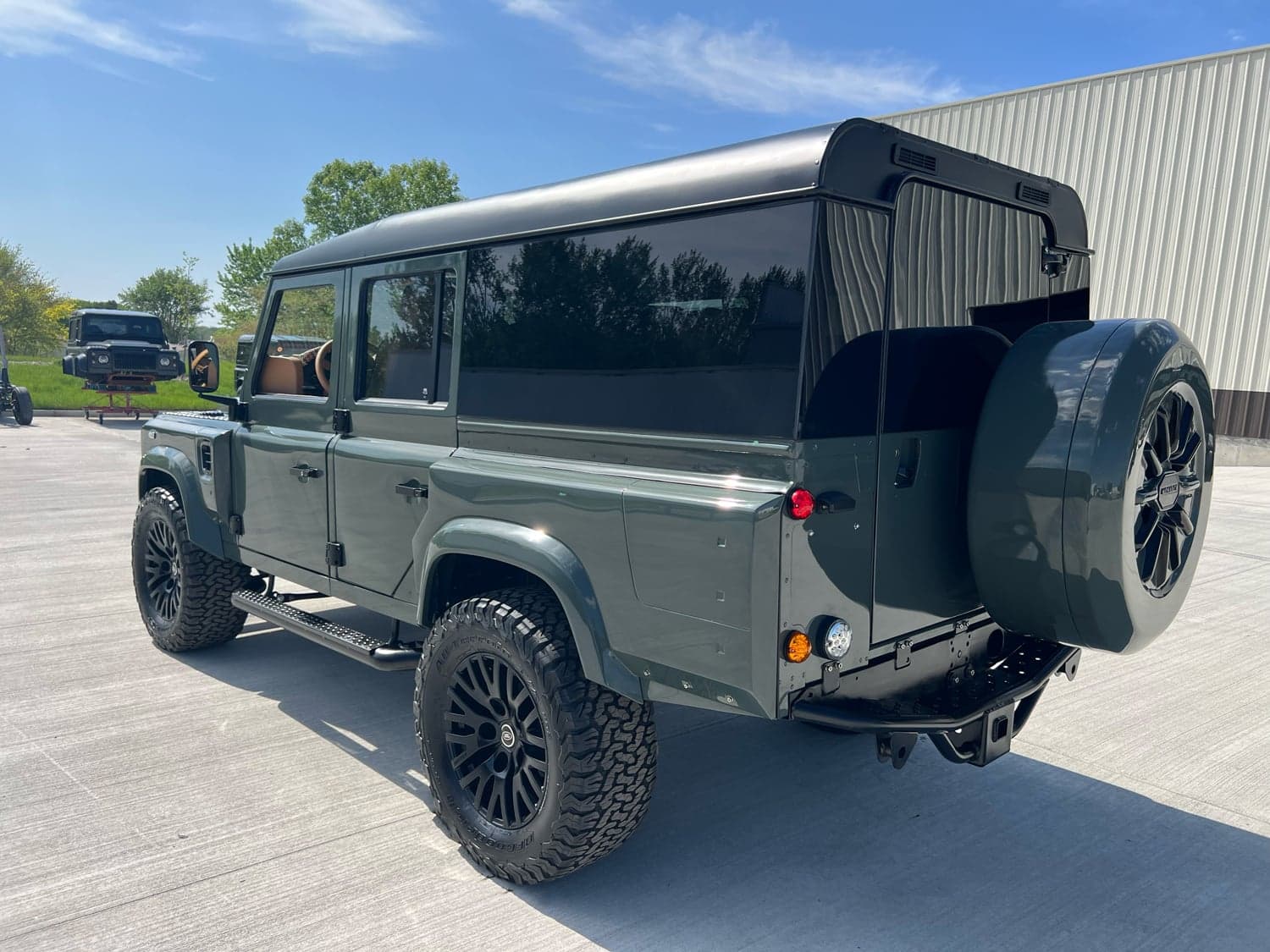 Rear View: Custom Land Rover Defender Rear view of a bespoke Land Rover Defender with a green finish and off-road tires