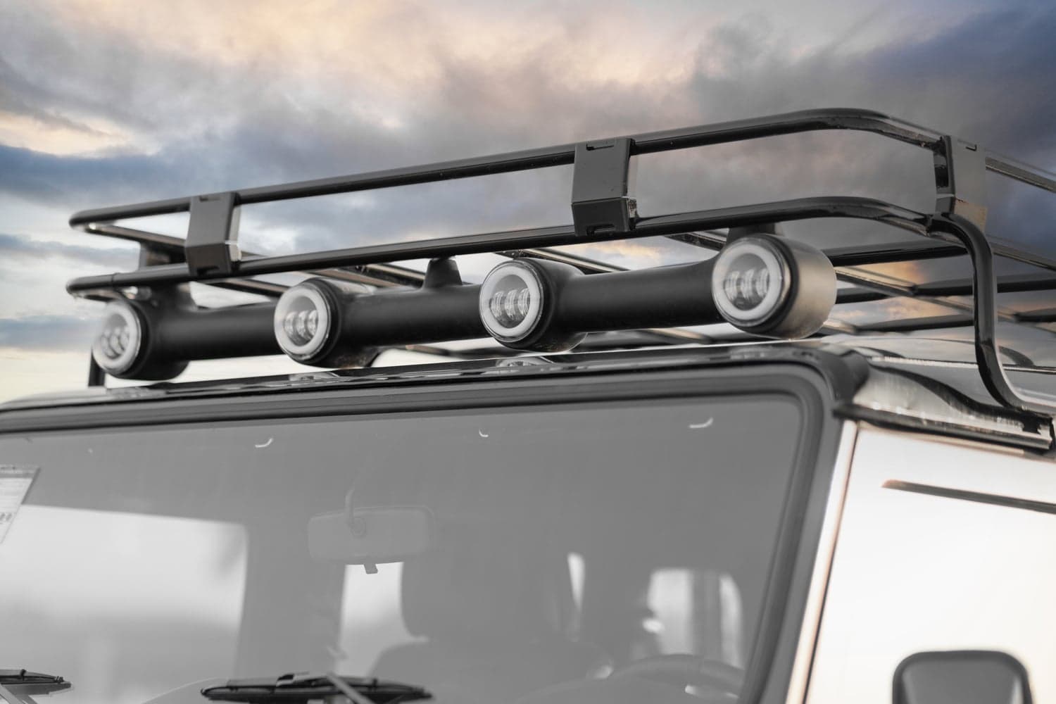 Detail Shot: Roof Rack with Lights Close-up of a custom Land Rover Defender roof rack featuring LED lights against a cloudy sky