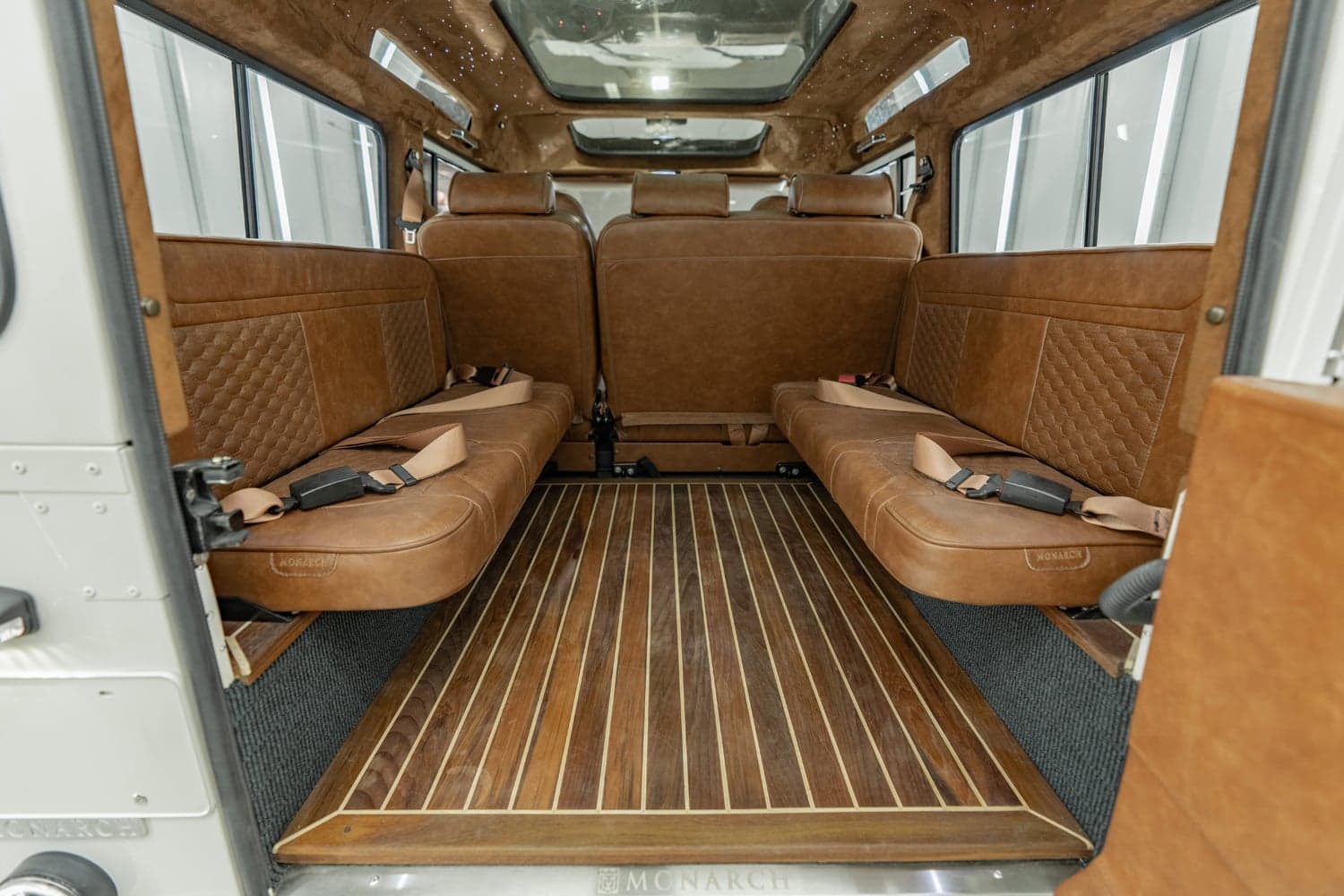 Interior Shot: Luxury Cabin Interior view of a custom Land Rover Defender with luxurious brown leather seating and wooden flooring