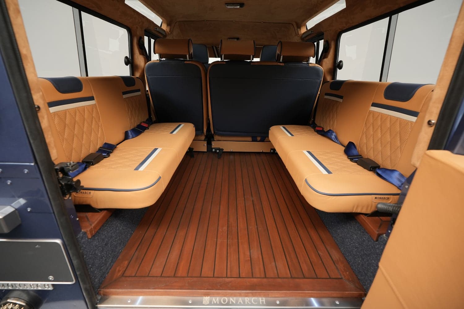 Interior Shot: Luxurious Rear Cabin Interior view of a luxury custom Land Rover Defender showcasing spacious tan leather seating and wooden flooring