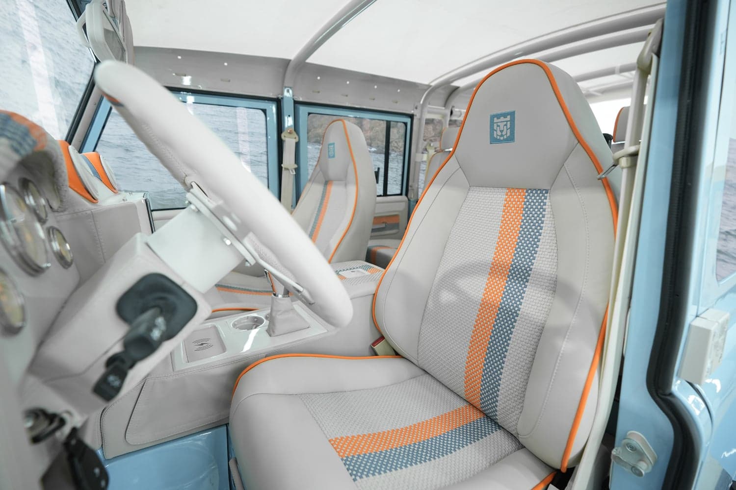 Interior Shot: Luxury Defender Cabin Luxury custom Land Rover Defender interior with white and orange accents, premium seating, and detailed dashboard.