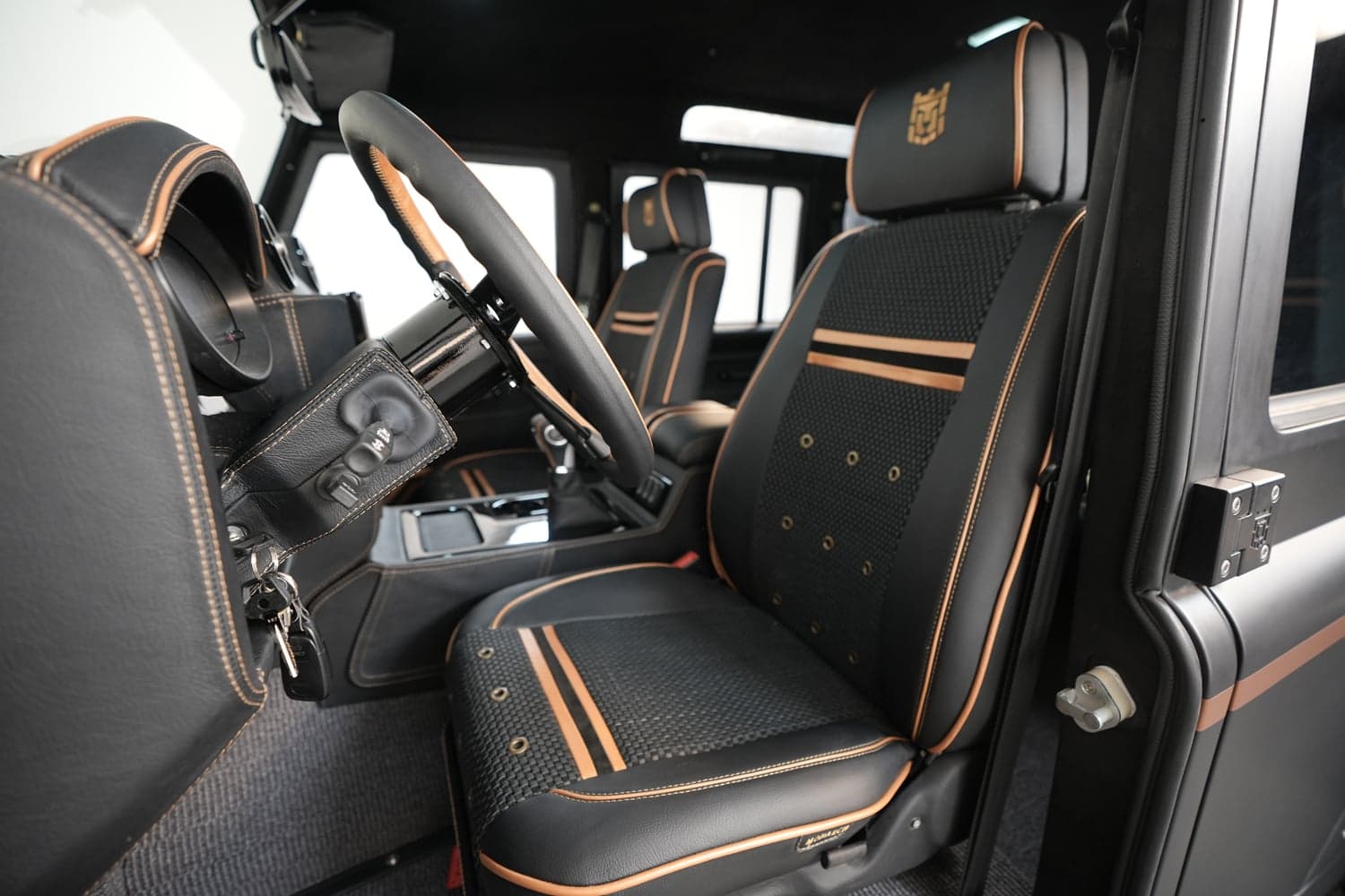Interior Shot: Luxurious Cabin Design Custom Land Rover Defender interior with premium black leather seats and orange stitching