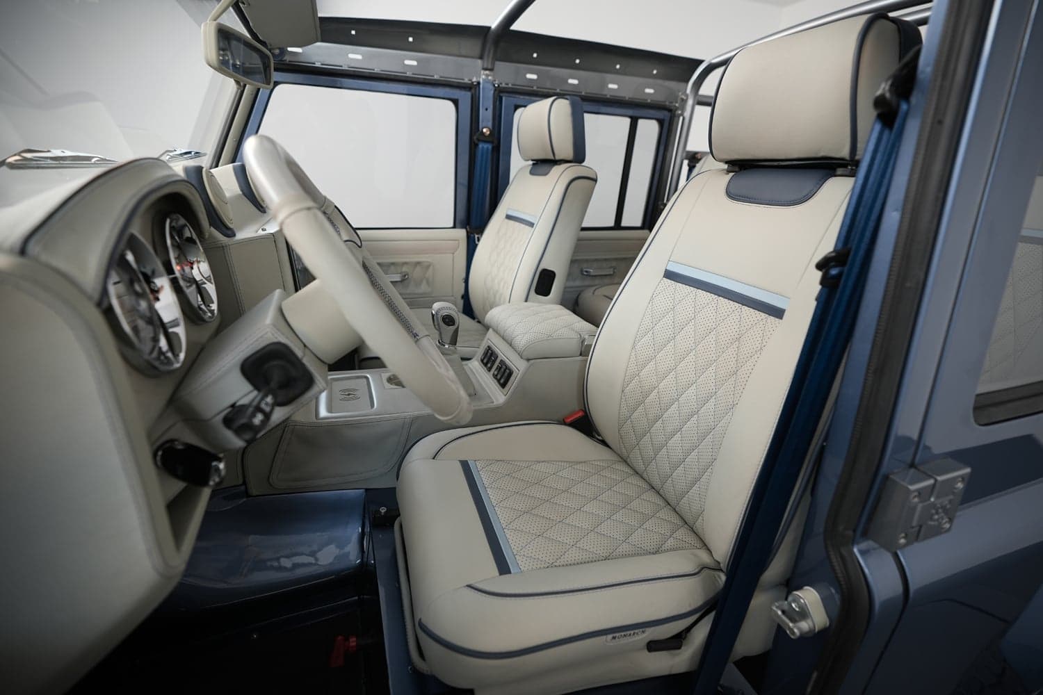 Interior Shot: Luxurious Cabin Design Interior view of a custom Land Rover Defender featuring premium beige leather seats with quilted design and modern dashboard.
