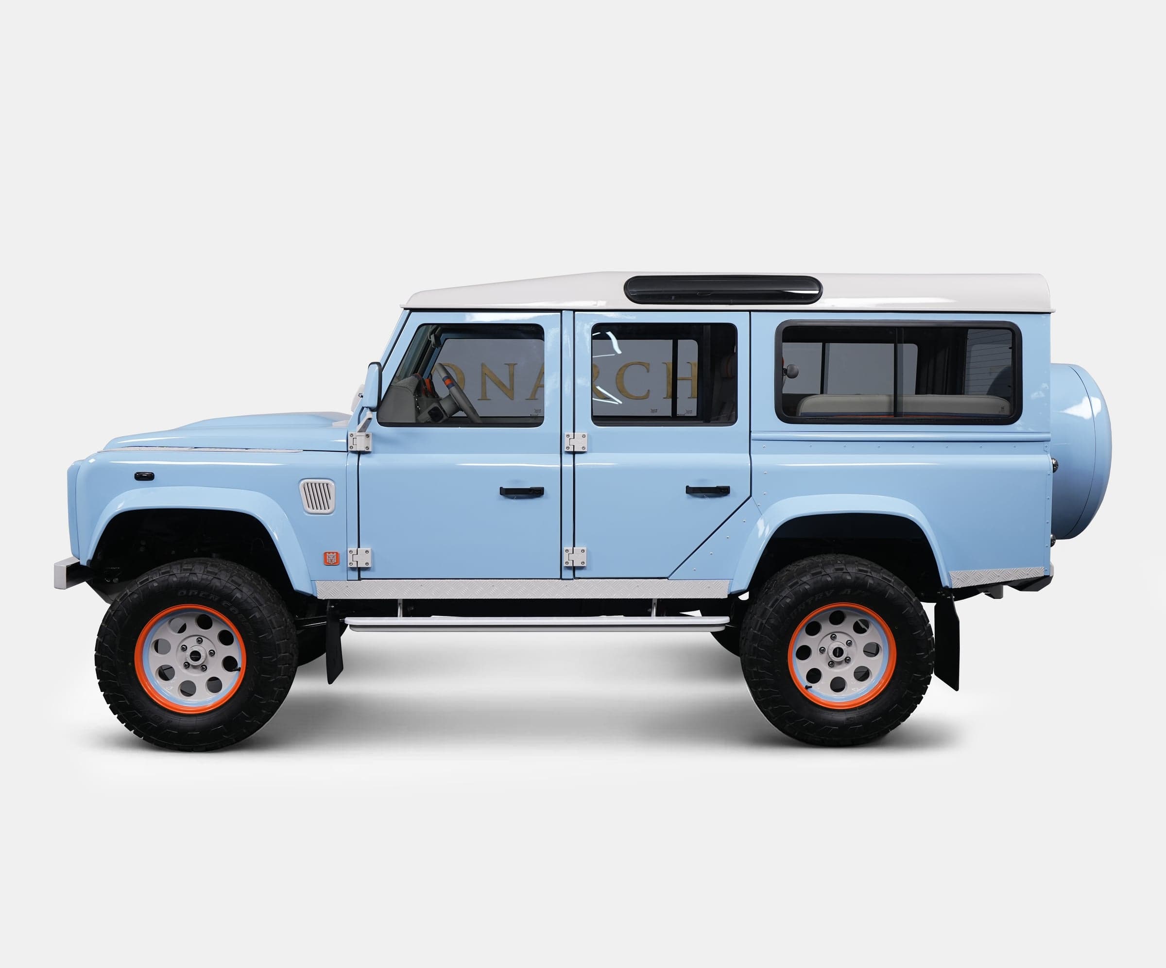 Side View: Custom Land Rover Defender Side view of a bespoke Land Rover Defender in light blue with a white roof and orange accents