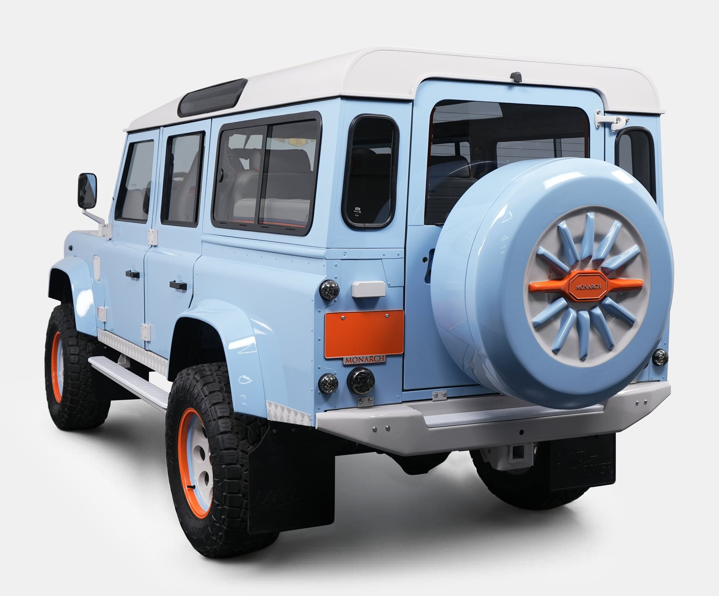 Rear View: Custom Land Rover Defender Rear view of a bespoke Land Rover Defender in light blue with orange accents