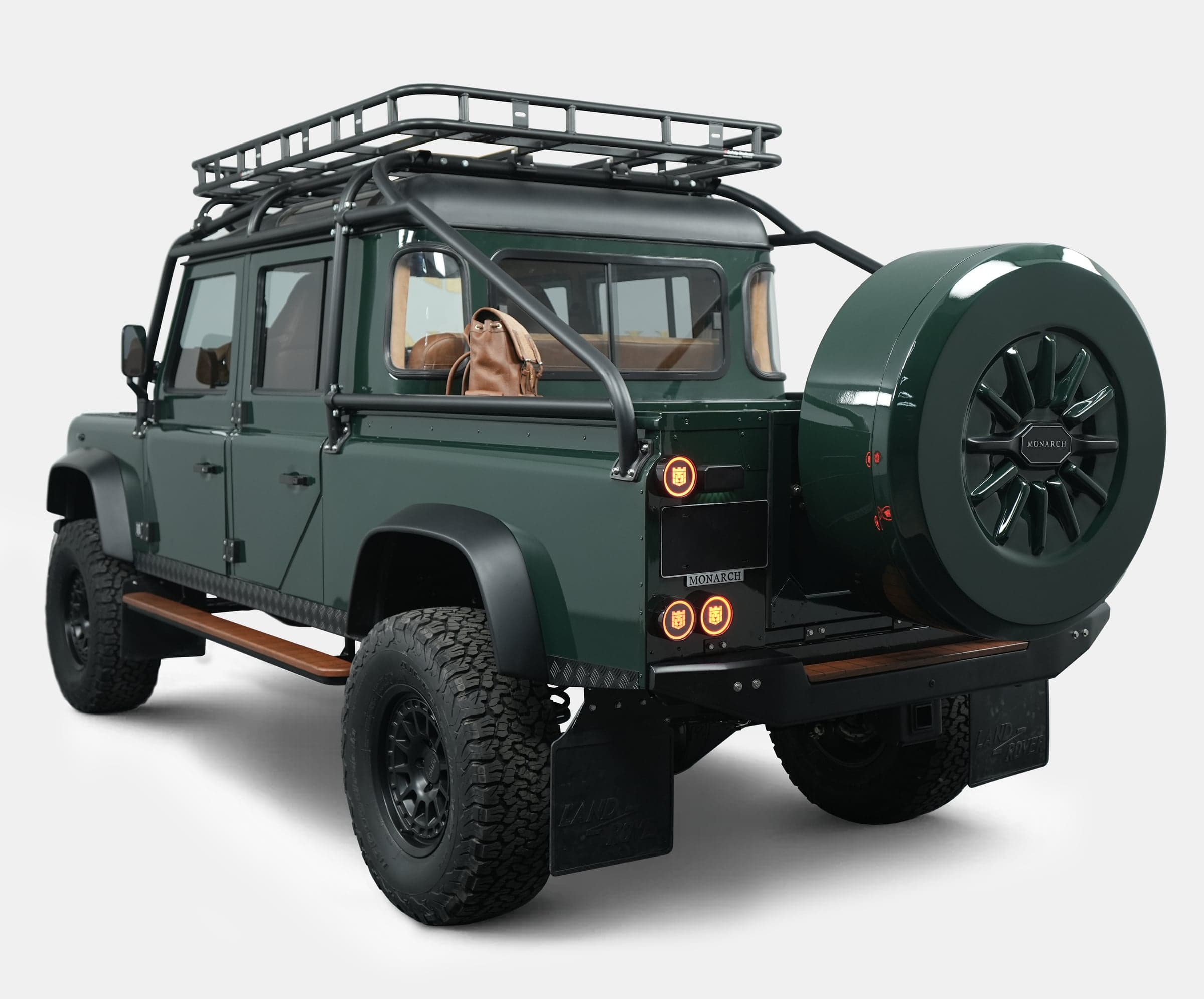 Rear View: Bespoke Land Rover Defender Rear view of a custom Land Rover Defender with a green finish and roof rack, showcasing luxury features