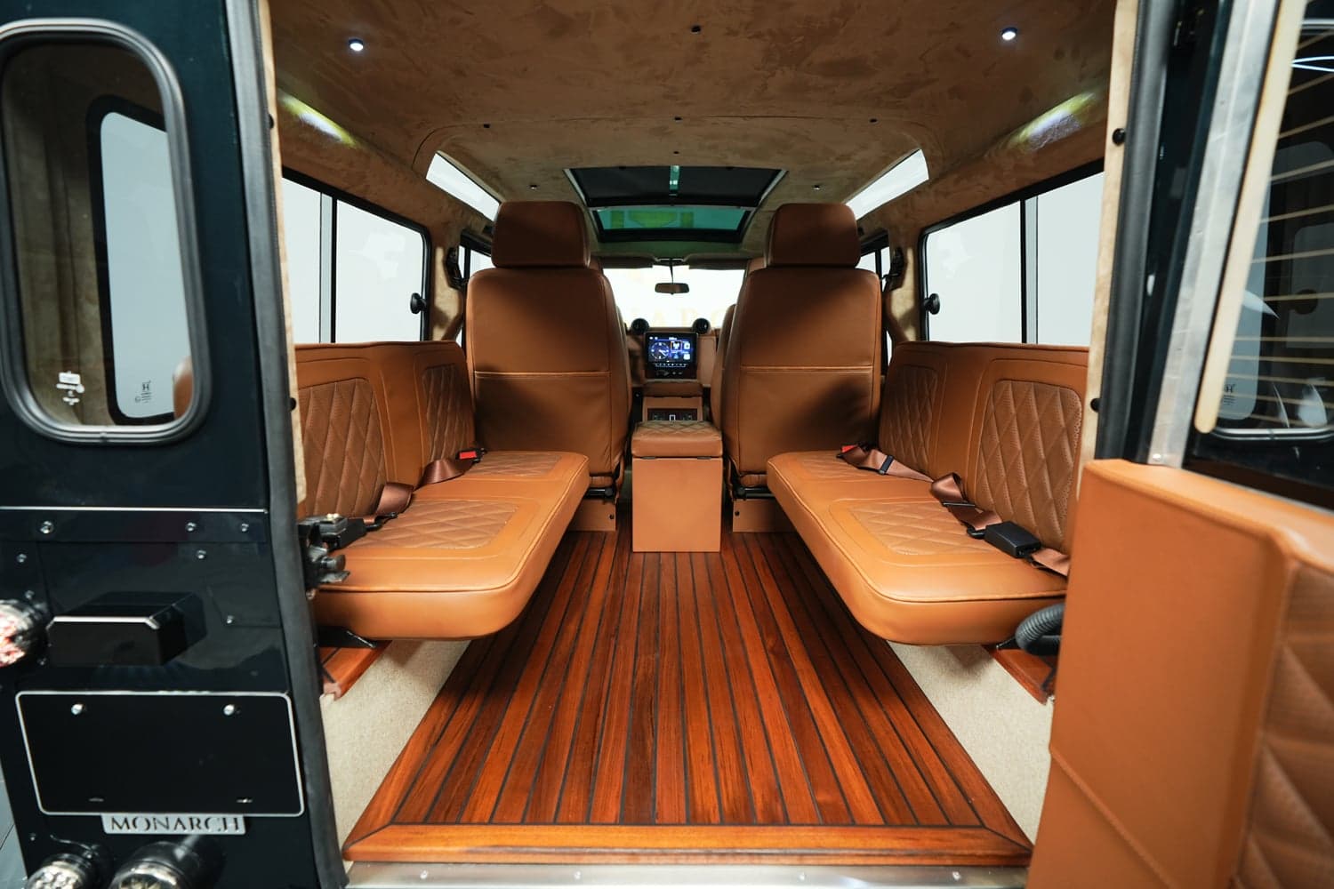 Interior Shot: Luxurious Cabin Design Bespoke Land Rover Defender interior with tan leather seating and wood flooring