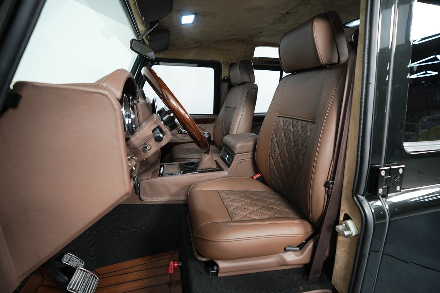 Interior Shot: Premium Cabin Luxury interior of a custom Land Rover Defender featuring brown leather seats and wood accents