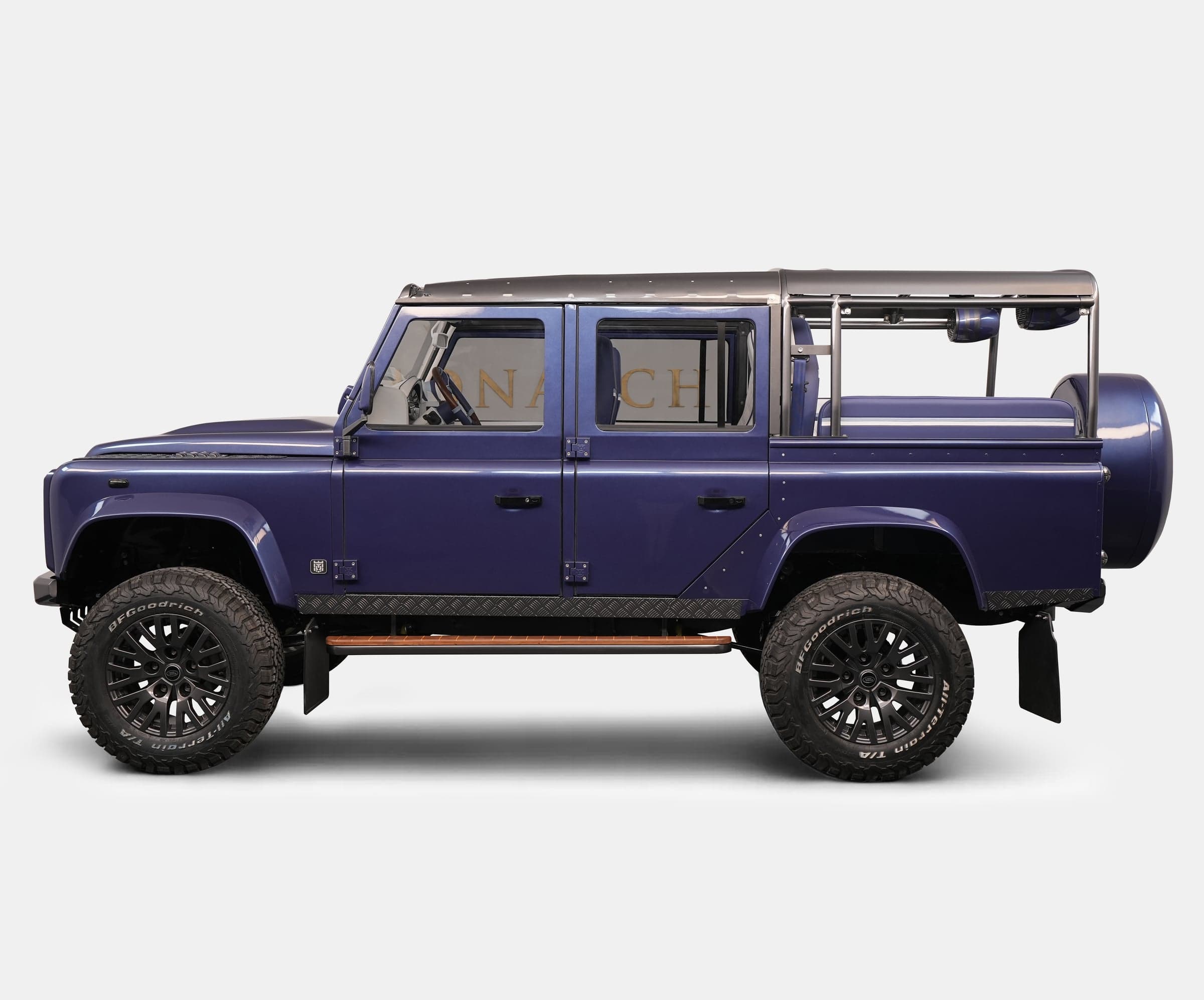 Side View: Custom Land Rover Defender Side view of a bespoke Land Rover Defender in deep purple with off-road tires and custom features