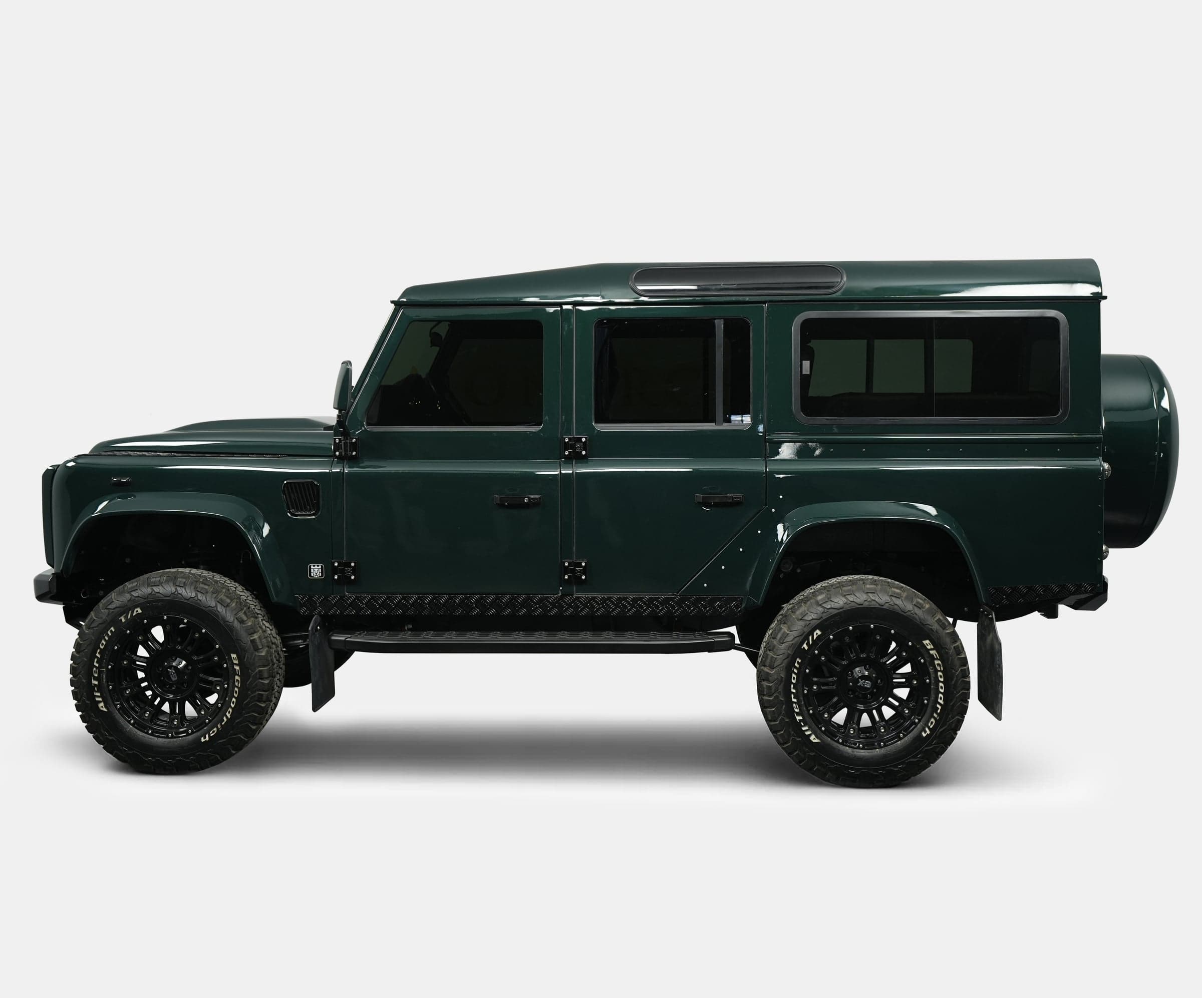 Side View: Bespoke Land Rover Defender Side profile of a custom Land Rover Defender in dark green with black wheels