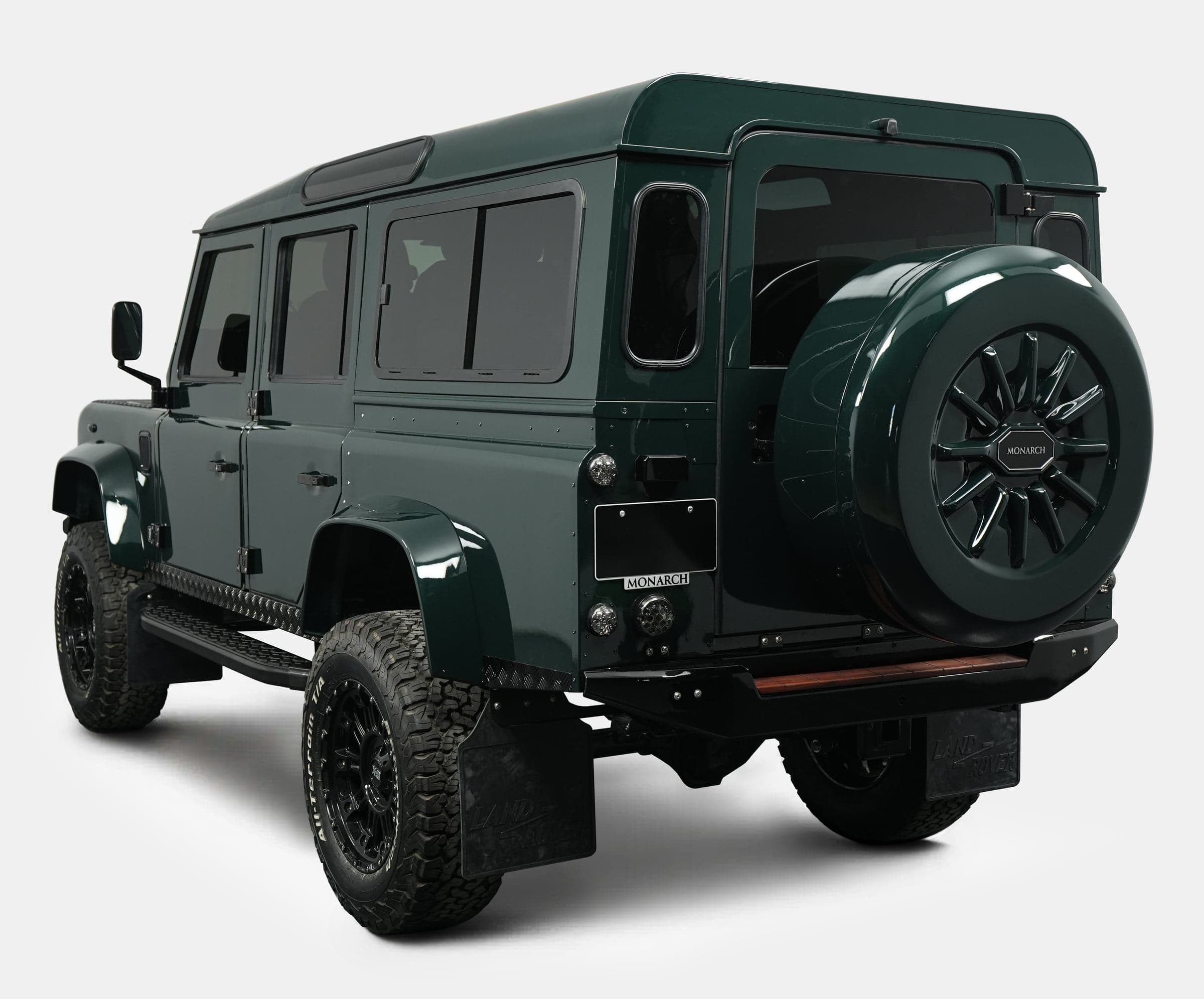 Rear View: Bespoke Land Rover Defender Rear view of a custom Land Rover Defender in dark green with a spare tire mounted on the back