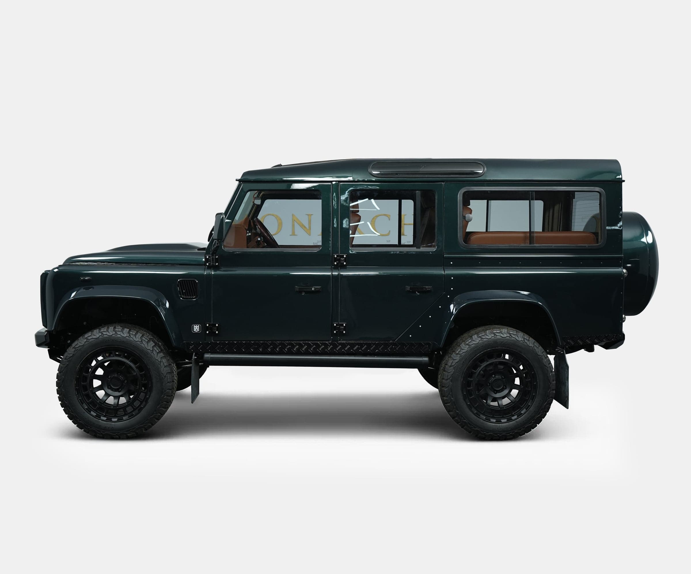 Side View: Custom Land Rover Defender Side view of a bespoke Land Rover Defender in dark green with luxury tan interior