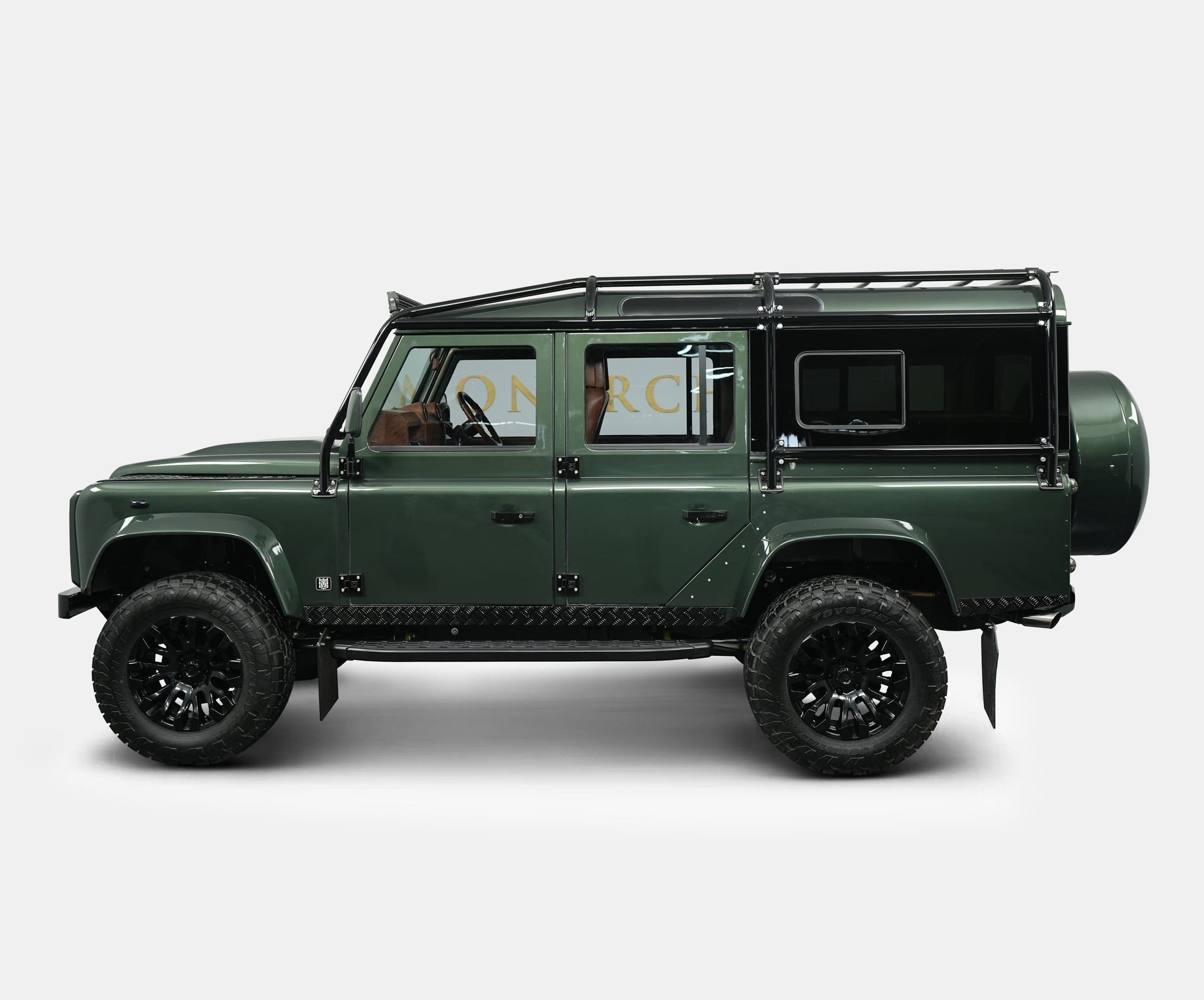 Side View: Custom Land Rover Defender Side view of a bespoke green Land Rover Defender with off-road tires and luxury details